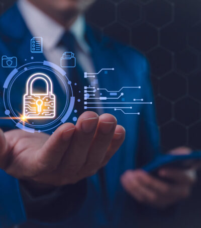 A businessman in a blue suit interacts with a futuristic holographic security interface, featuring a glowing padlock symbol, signifying advanced digital protection. Secure business networks